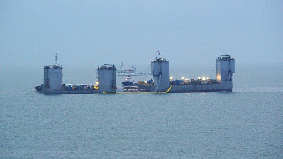 A handout photo released by the South Korean Maritime Ministry showing two barges bringing the sunken Sewol ferry back to surface, in the sea off Jindo island on 23 March 2017.