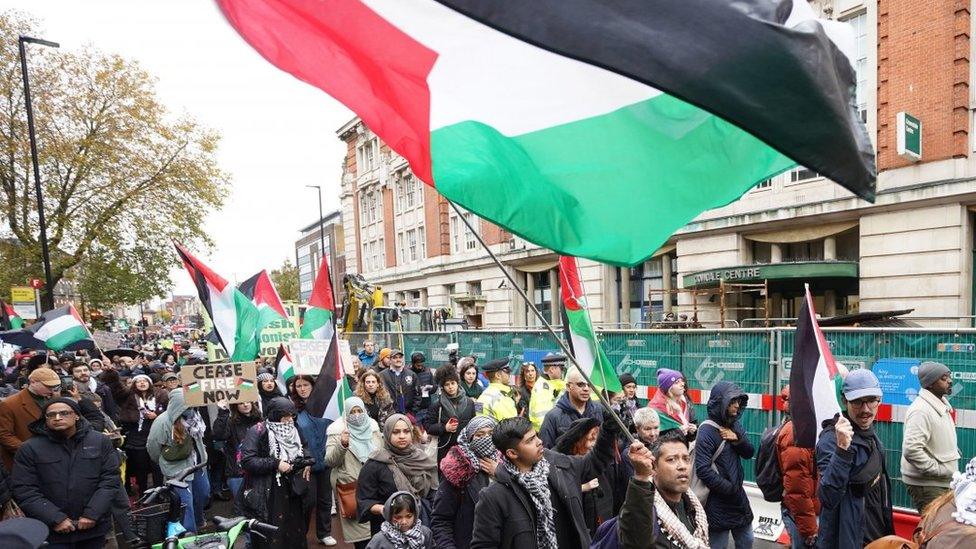 Crowds marching under several Palestinian flags in Camden