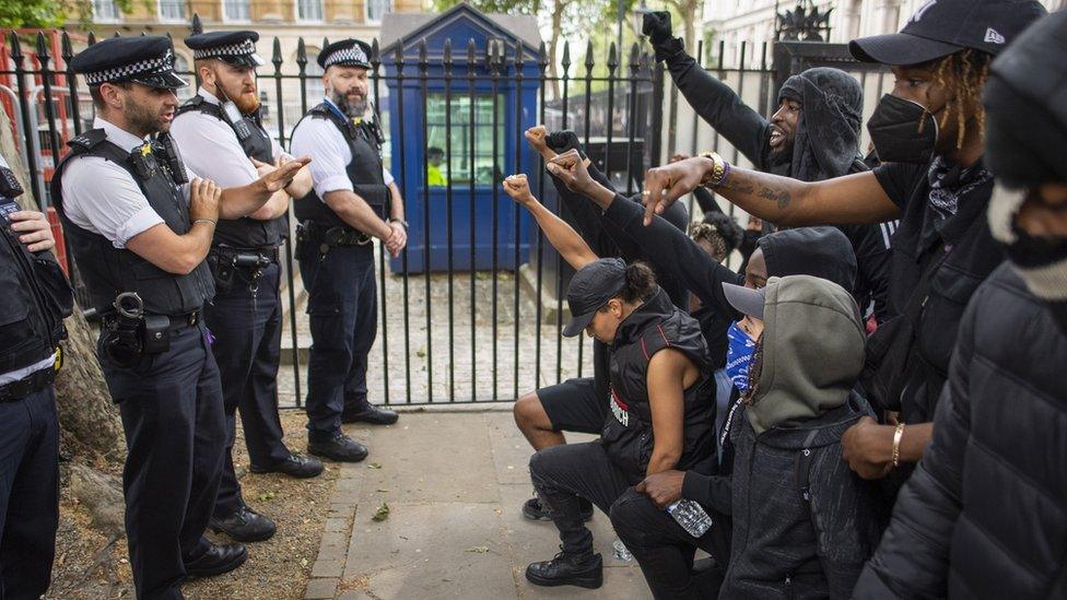 Black protesters kneeled in front of police