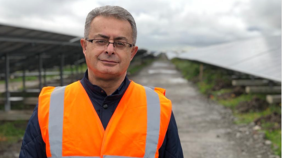 Cllr Michael looking at the camera with the solar farm behind him