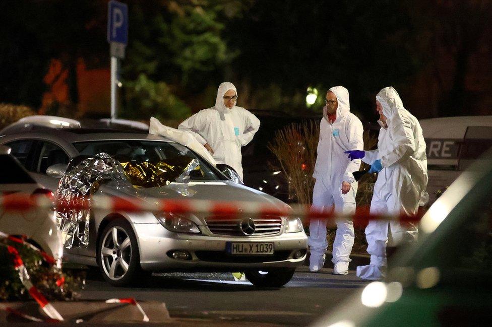 Forensic experts examine a damaged car after a shooting in Hanau near Frankfurt, Germany, 20 February 2020.