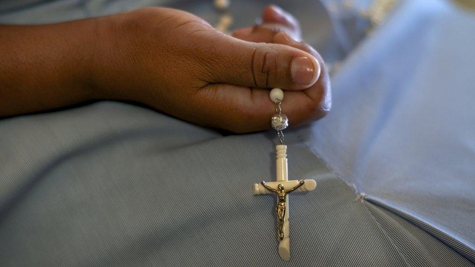 A nun holds a set of rosary beads