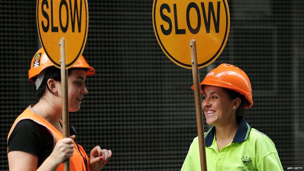 Workers hold traffic flow control signs outside a construction site in central Sydney