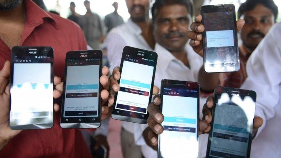 Indian drivers for Uber show mobiles phones given to them by the company during a one-day hunger strike against the US-headquartered transportation service in Hyderabad on August 28, 2015.