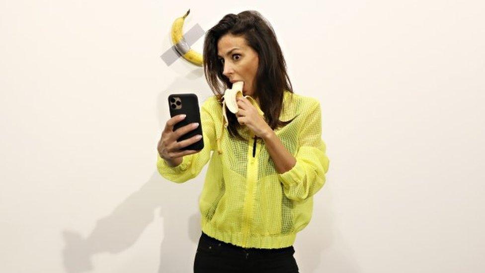 Woman eating banana takes selfie with a banana taped to a wall that sold for $120,000