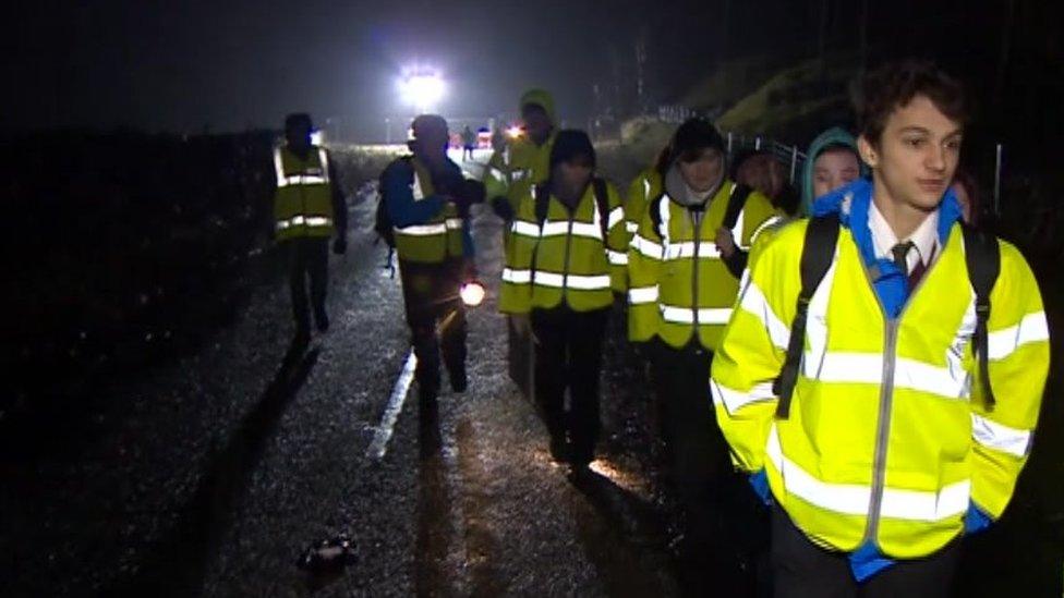 Pupils make their way along a temporary path on the A591