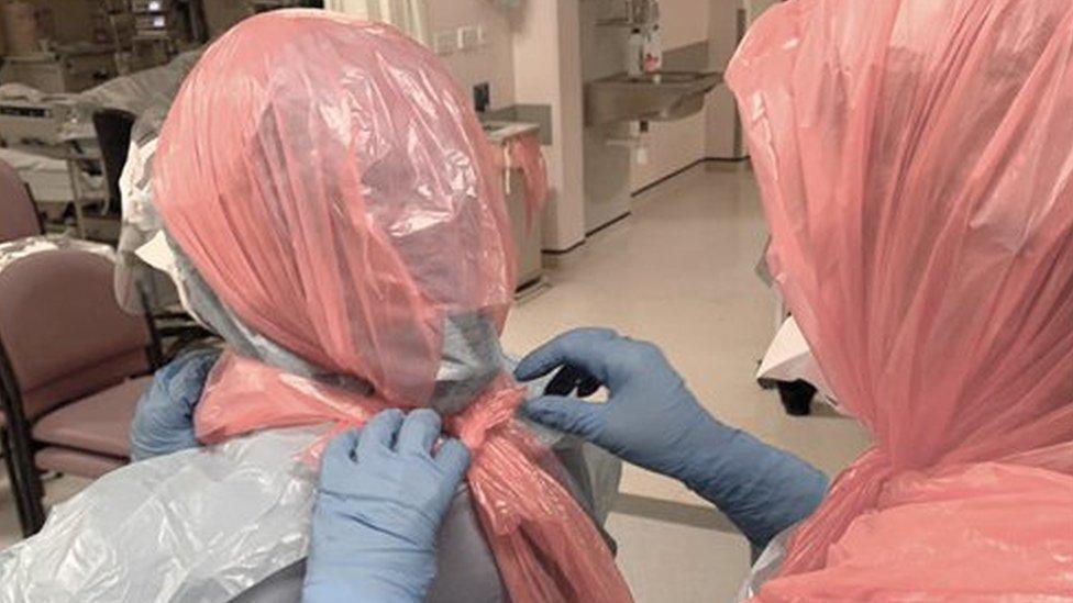 Photo of Dr Roberts helping her colleagues by securing bin bags on their heads