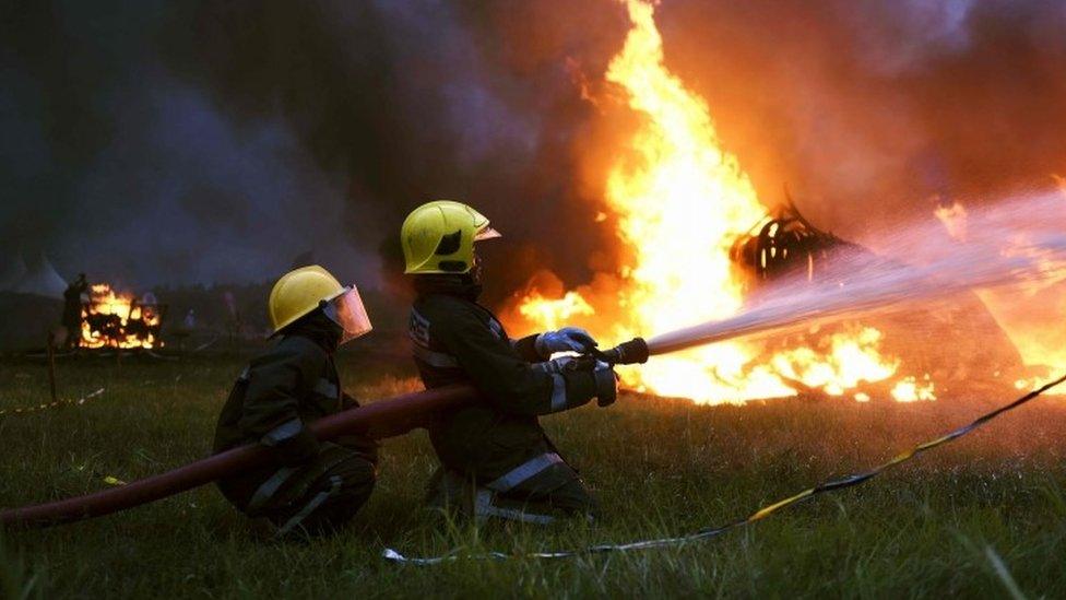 Firefighters help put out the fire at the ivory burning