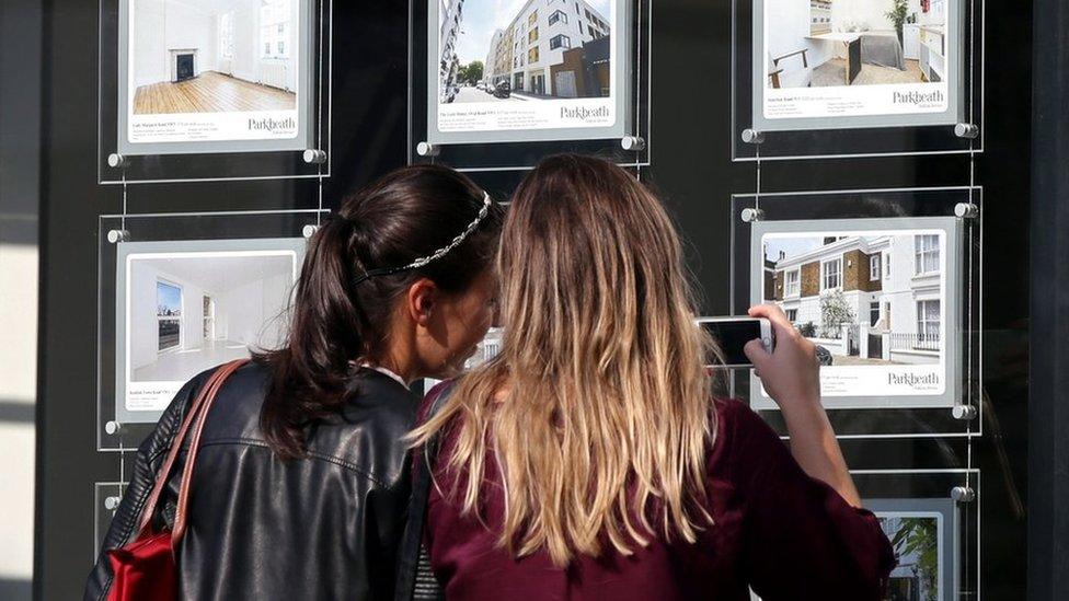 Two women study houses for sale