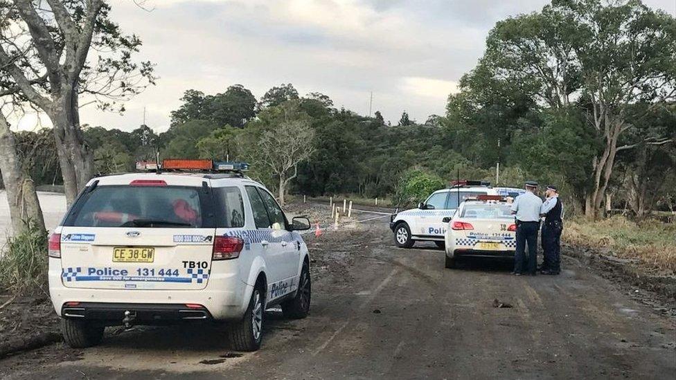 Police guard the site where a car left the road and entered the Tweed River.