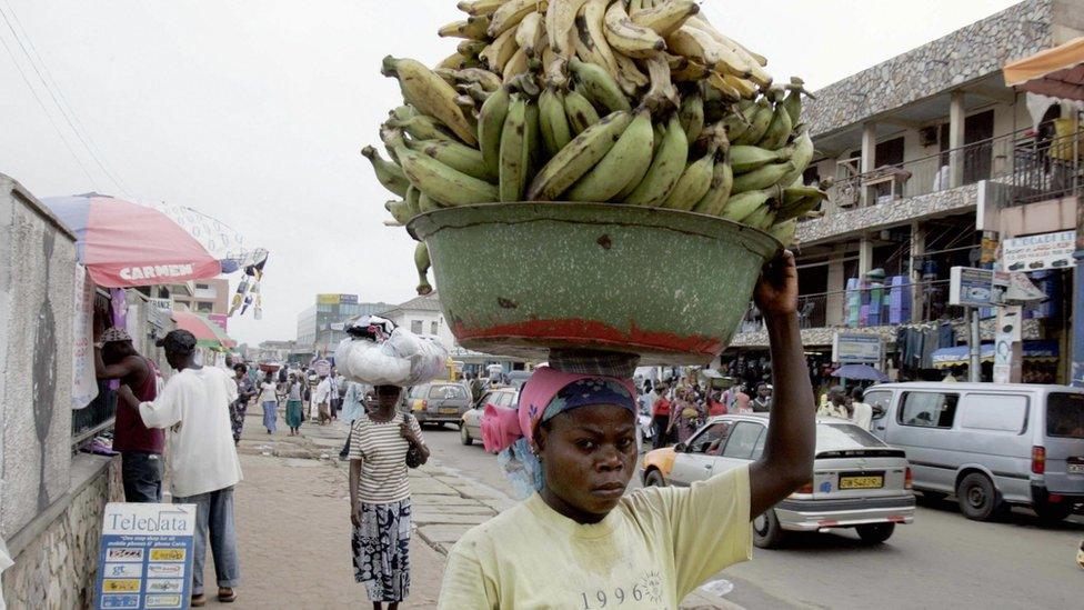 A Ghanaian woman carries a heavy load of bananas in Accra market