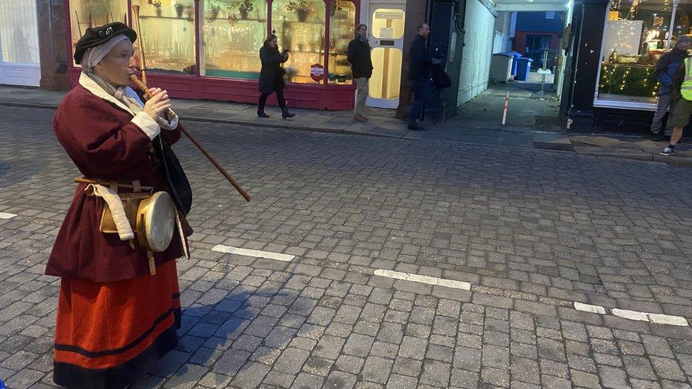 Woman in red Tudor dress plays wind instrument