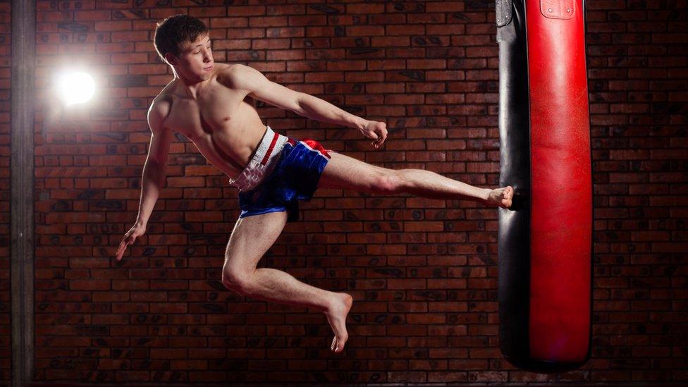 Man in shorts kicking a punchbag