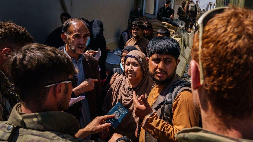 Afghan refugees try to go past a security check point manned by British security forces at the Abbey gate, in Kabul, Afghanistan