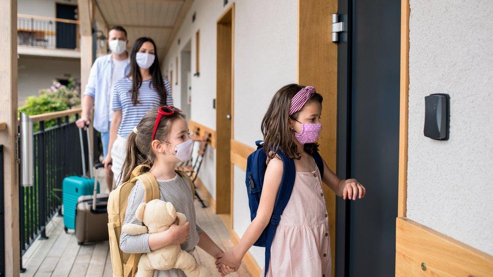 A family on holiday wearing masks checking into a hotel