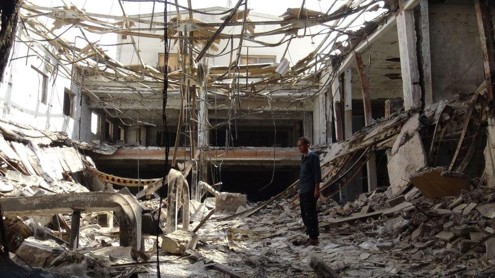 A man stands inside a factory damaged during fighting in the Yemeni port city of Hudaydah (17 December 2018)