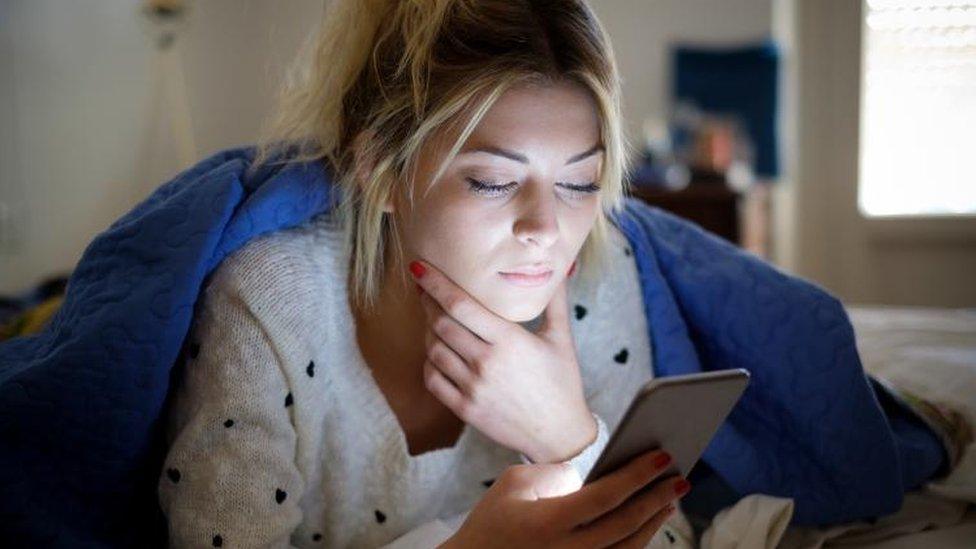 Woman with smartphone in bed