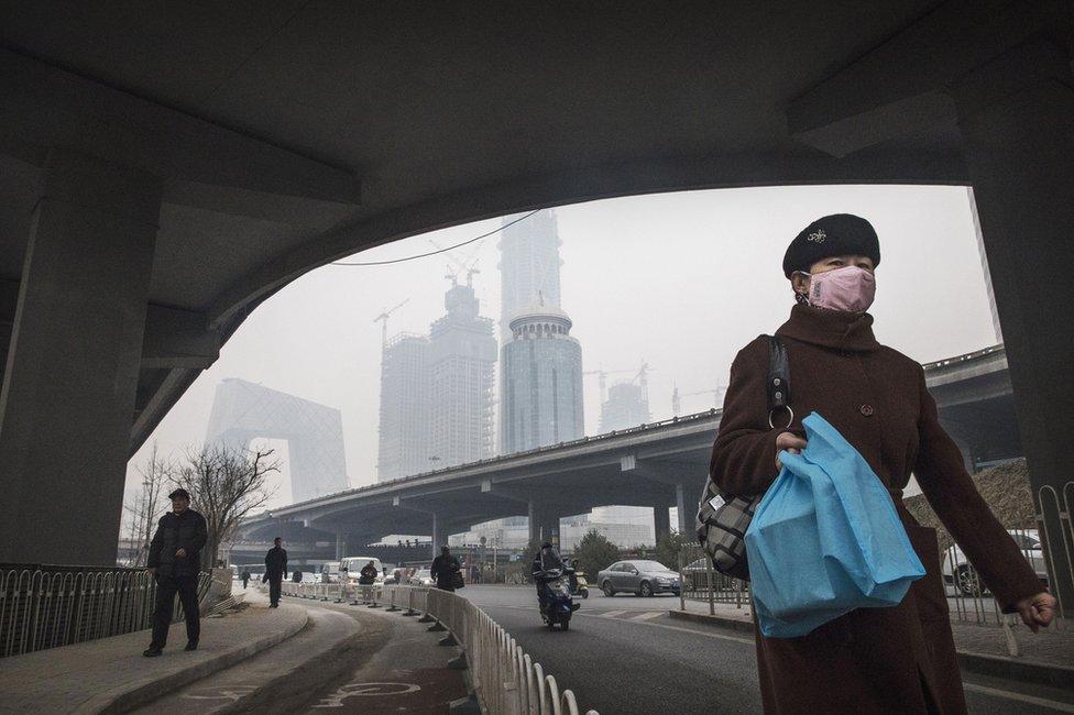 A Chinese woman wears a mask as she walks in the street on a polluted day on 12 December 2016 in Beijing, China.