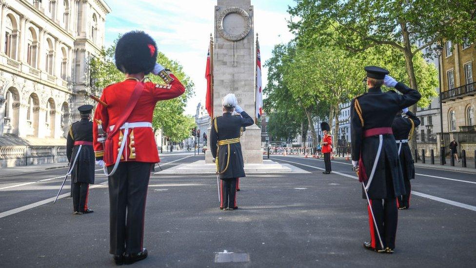 Members of the armed forces are seen saluting during a service at the Cenotaph on Whitehall