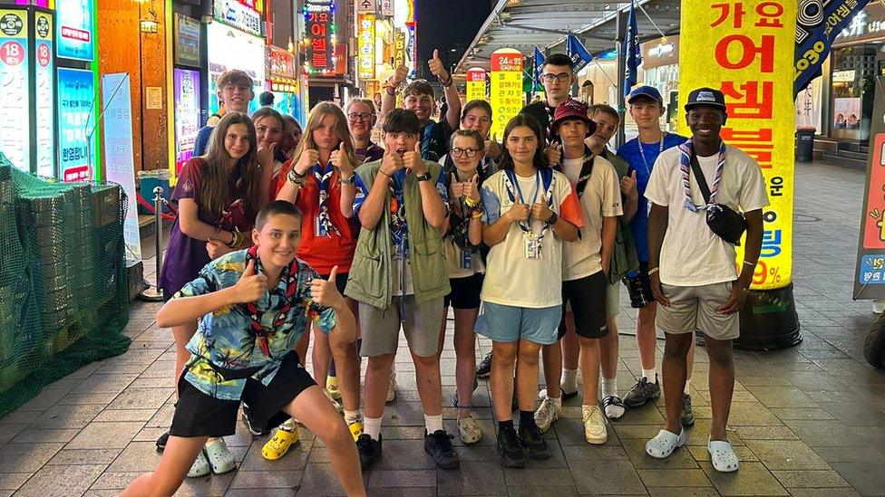 Bedfordshire Bees pose for the camera, thumbs aloft, in a Seoul street