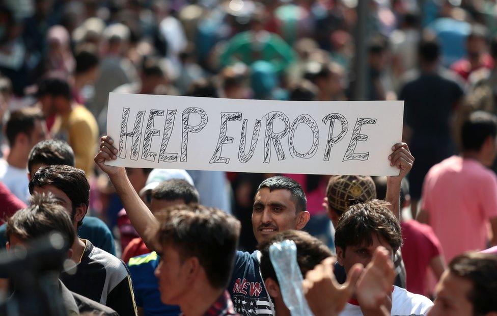 A man holds a placard reading 'Help Europe' outside the Keleti (East) railway station in Budapest