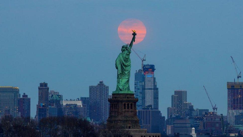 The last supermoon of 2019 'Super Worm Equinox Moon' rises behind the Statue of Liberty in New York