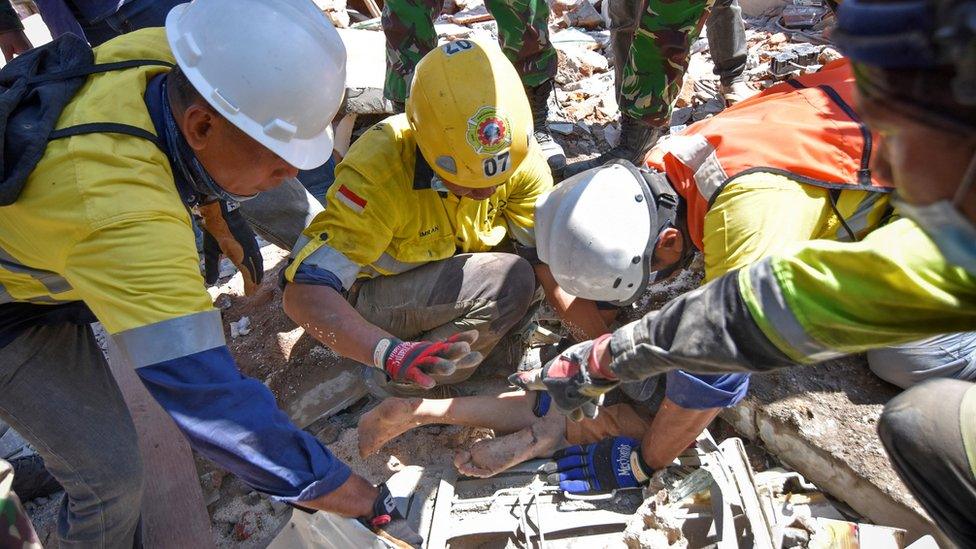 Rescue workers remove a woman alive from the rubble of a building in Tanjung, North Lombok (7 Aug 2018)