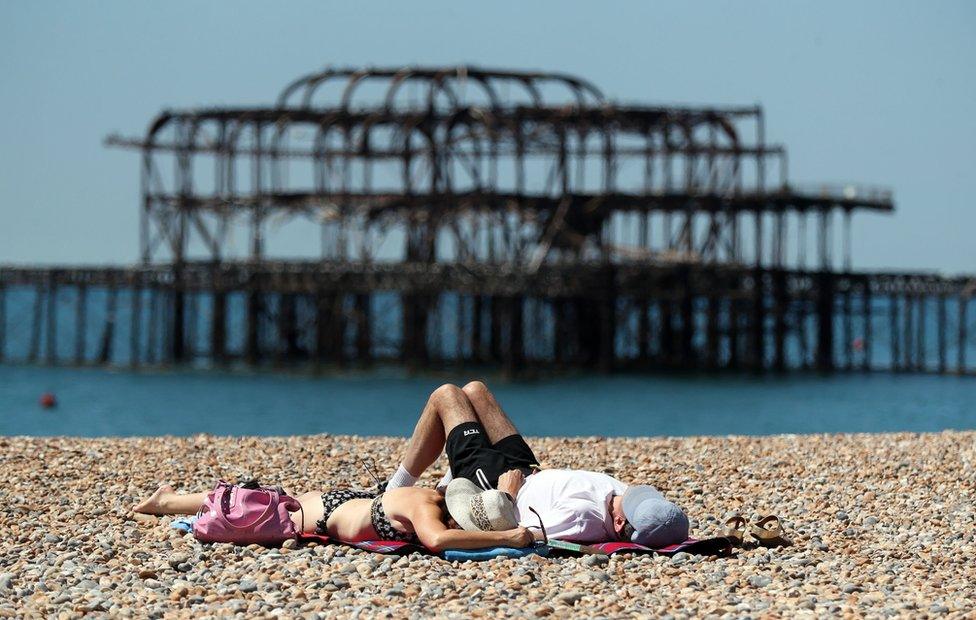 People relax in the sunshine on the beach in Brighton, Sussex