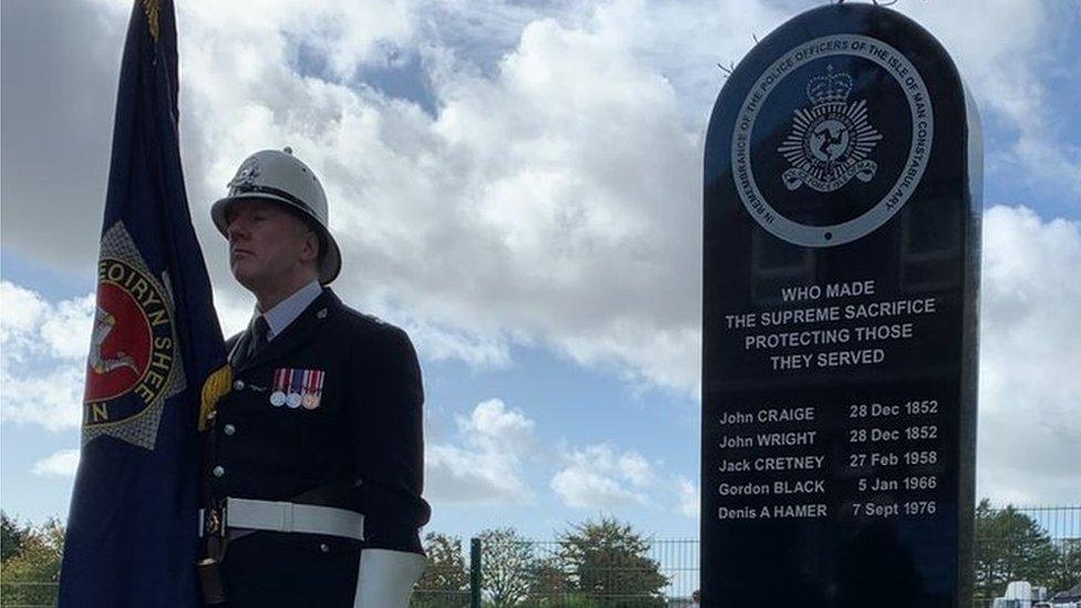 Flag bearer standing next to memorial