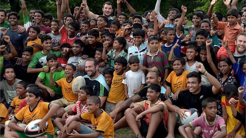 Players of the British rugby team Harlequins pose for a photo with children in Kolkata