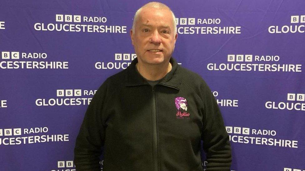 Nick Gazzard stood smiling in front of BBC Radio Gloucestershire backdrop