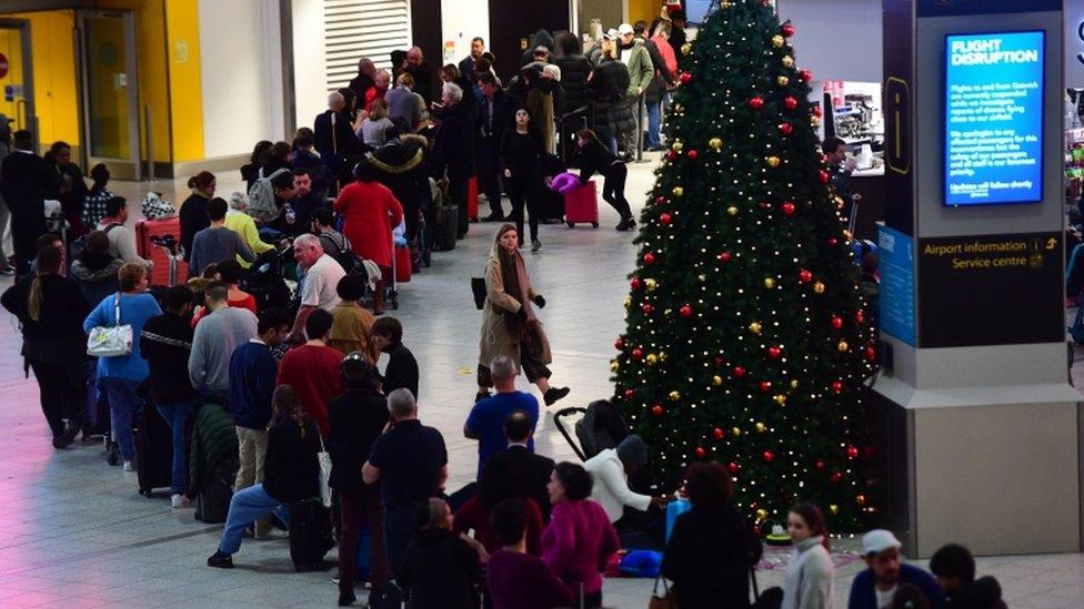 Passengers stranded queue for information at Gatwick airport which has been closed after drones were spotted over the airfield last night and this morning