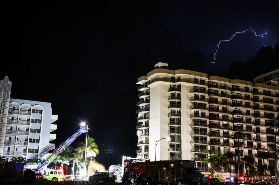 A lightning strikes above the Champlain Towers South as Search and Rescue personnel work after the partial collapse of the Champlain Towers South in Surfside, north of Miami Beach, on June 24, 2021