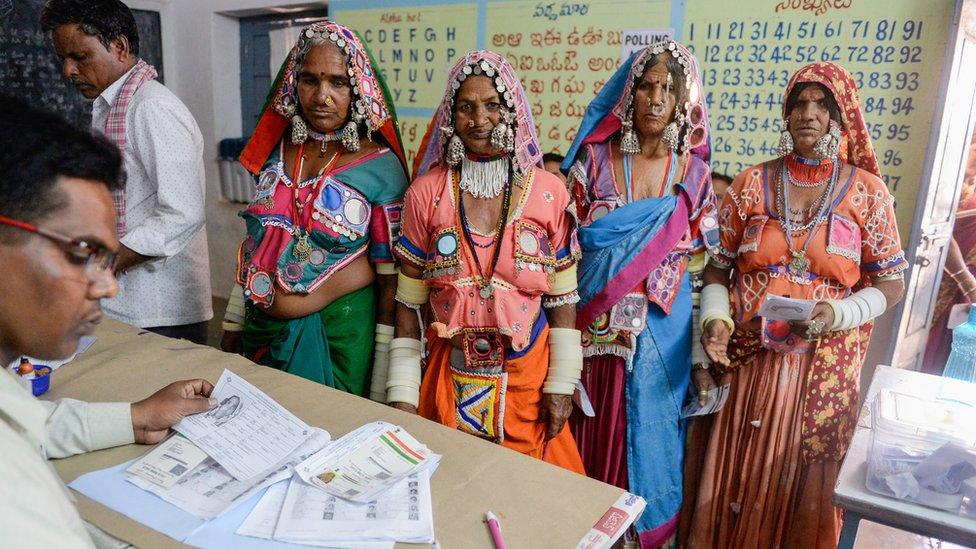 An official checks the names of Indian lambadi tribeswomen at a polling station during India's general election at Pedda Shapur village on the outskirts of Hyderabad on April 11, 2019.