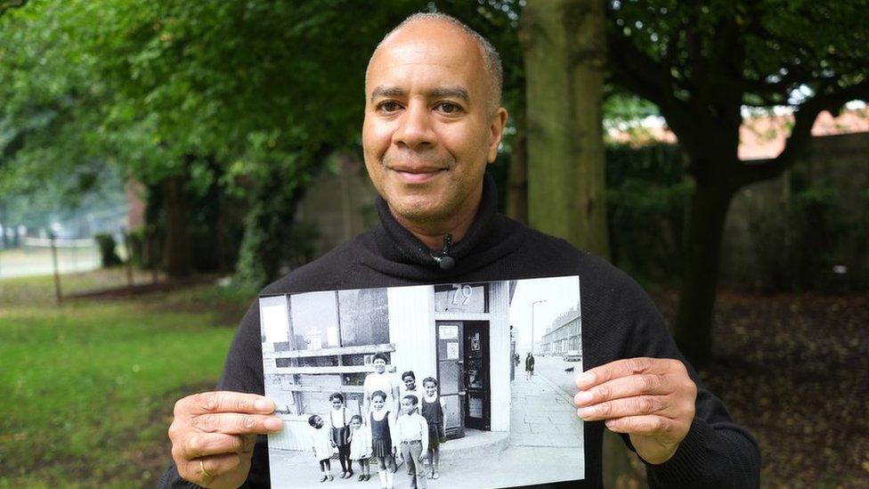 man poses with picture of when he was young