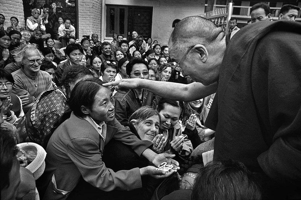 ​The courtyard between the temple and the palace​ ​complex is thronged with visitors. Here he talks to a Tibetan lady​ ​in need of a special blessing.