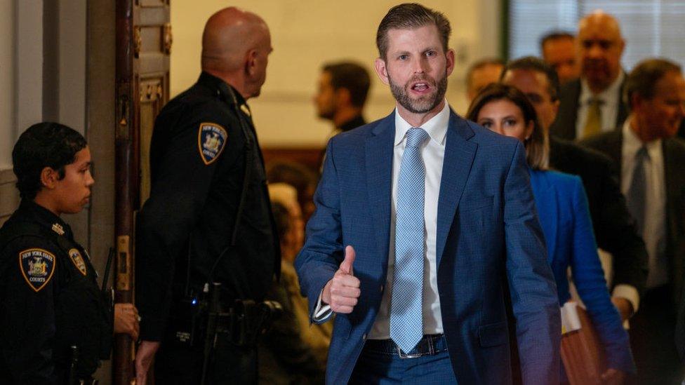 Eric Trump, navy suit and blue tie, gives thumbs up