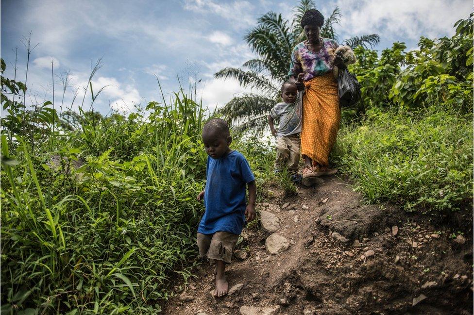 Criscent Bwambale’s grandmother leads him by the hand