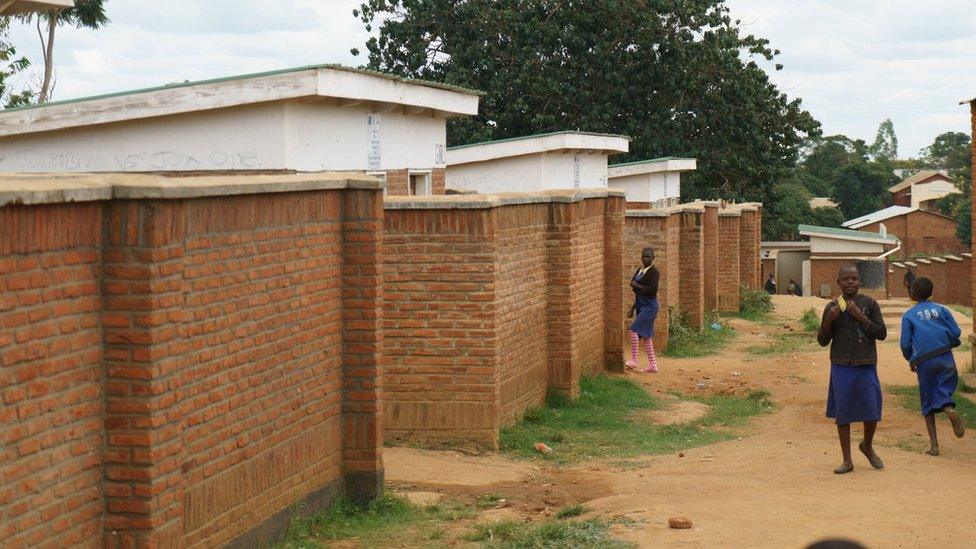 A row of red-brick toilet blocks stretches down the earthen path in Mloza school, as students make their way to and from class