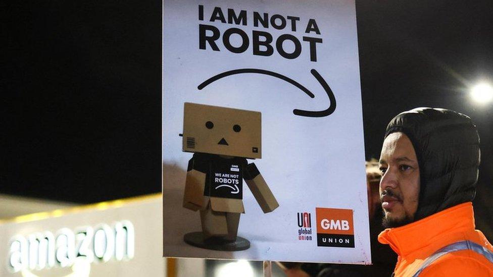 A man holds a sign during a rally in support of Amazon workers on strike, outside the Amazon warehouse, in Coventry, Britain, on 25 January 2023