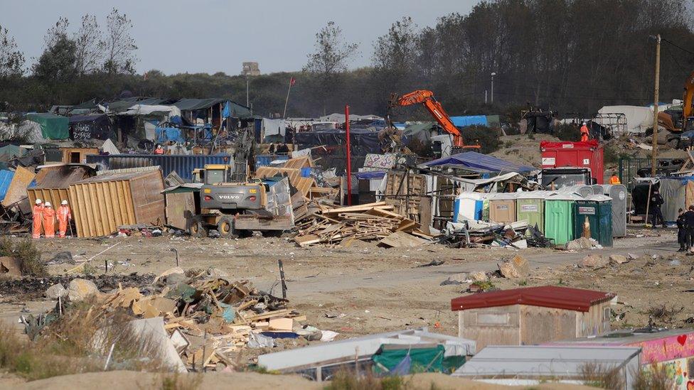 A bulldozer clearing make-shift structure in Calais 'Jungle'.