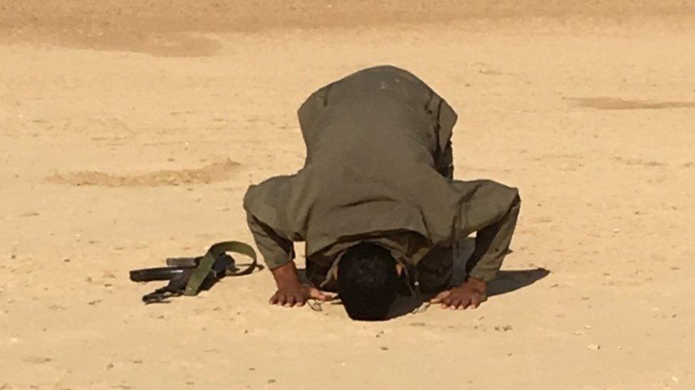 Shia fighter prays during a break in an assault on IS targets in mainly Sunni villages