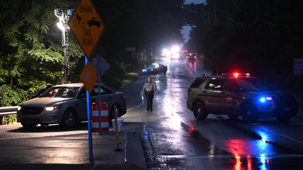 Police monitor a wooded perimeter during the manhunt