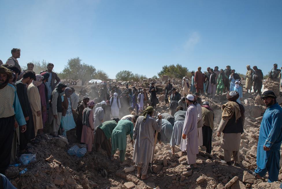 People watch as rescue teams search for survivors under the rubble at Siah Ab