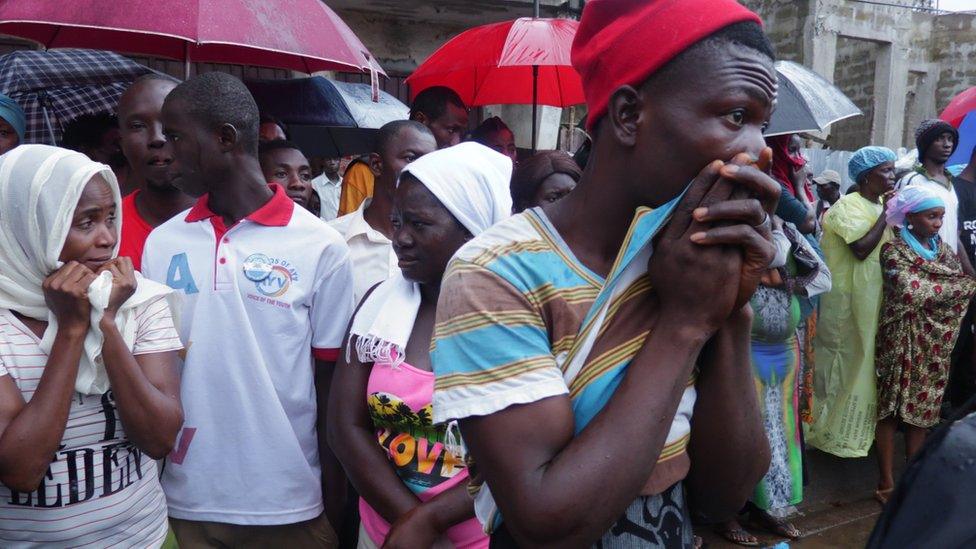 Relatives wait on the pavement opposite the morgue in the hopes of being able to identify the bodies of loved ones