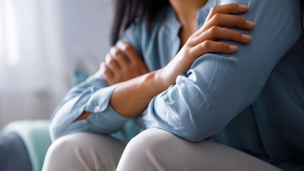 Midsection of unrecognizable young woman hugging herself to comfort