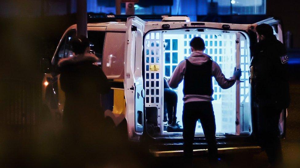 Police officer looking into the back of a police van