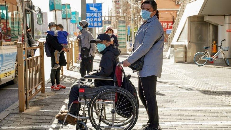 Chinese people wear protective masks as they wait for the bus