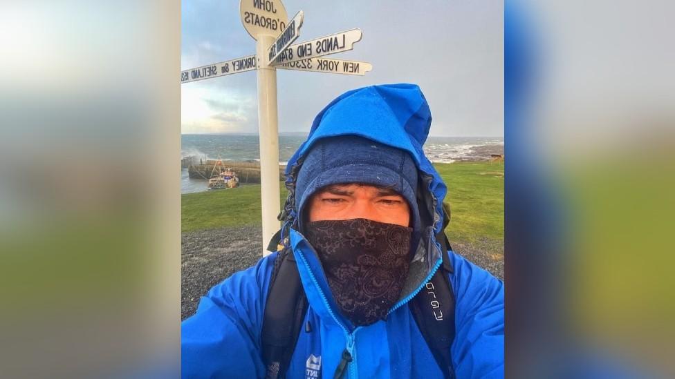 Chris Howard in front of a sign at John O'Groats