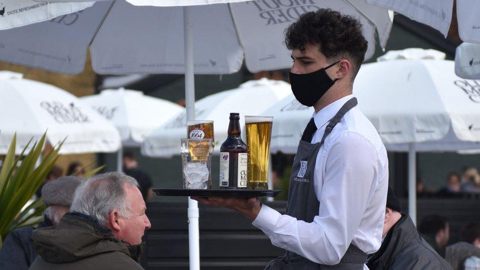 Barman delivering a pint outside in facemask